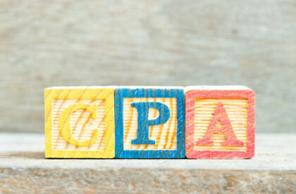 Three wooden alphabet letter blocks lined up to spell "CPA." The "C" is yellow, the "P" is blue, and the "A" is red.