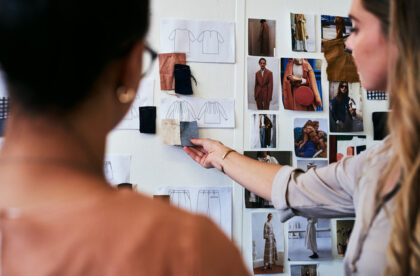 A fashion student in college showing a professor an example of fabric she might pair with her shirt design.