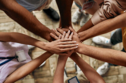 A top view of a group of people standing in a circle. They are putting their hands on top of each other.