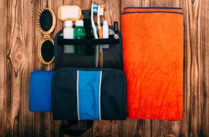 A hygiene kit featuring toothbrushes, mouthwash, chapstick, and a brush. The items are laid on a wooden surface.