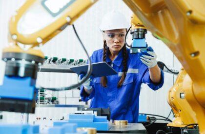 A close-up of a female student studying and inspecting a robot arm used for automation in a factory workshop.