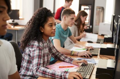 A group of college students sitting at desks in a computer lab while working on design projects independently.